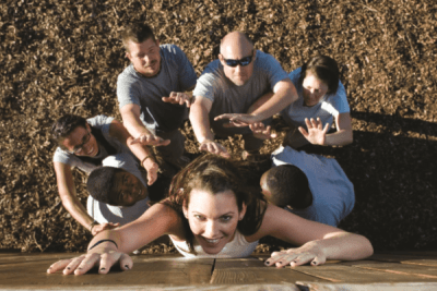 group of students and instructor working on overcoming an obstacle at the challenge course